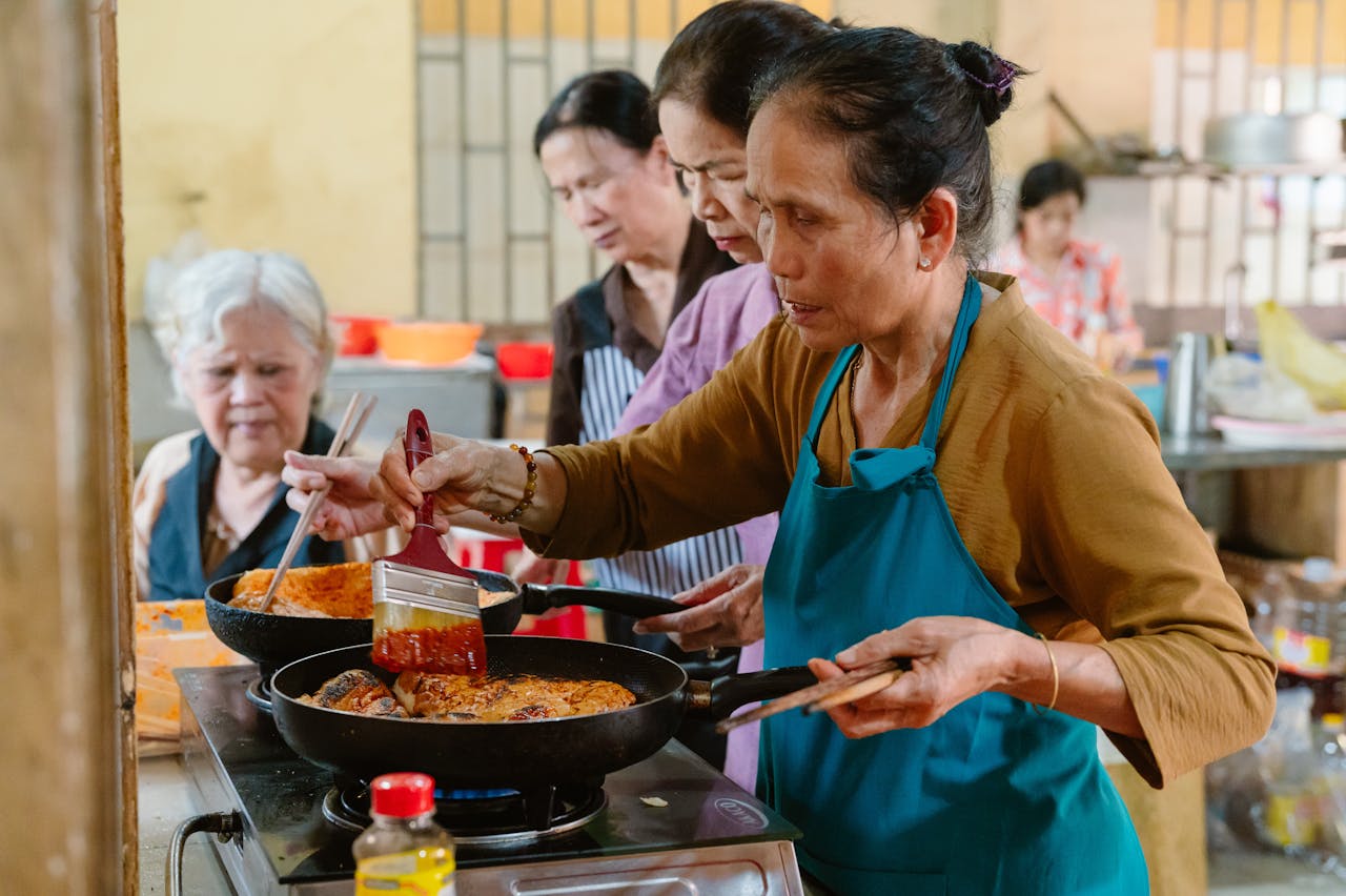 A diverse group of women cooking together in a social setting, fostering community and cultural exchange.